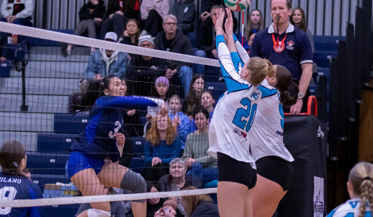Stephanie Sung gets an attack past a pair of VIU blockers during a weekend set in Nanaimo. (Matt Carter/VIU Athletics)